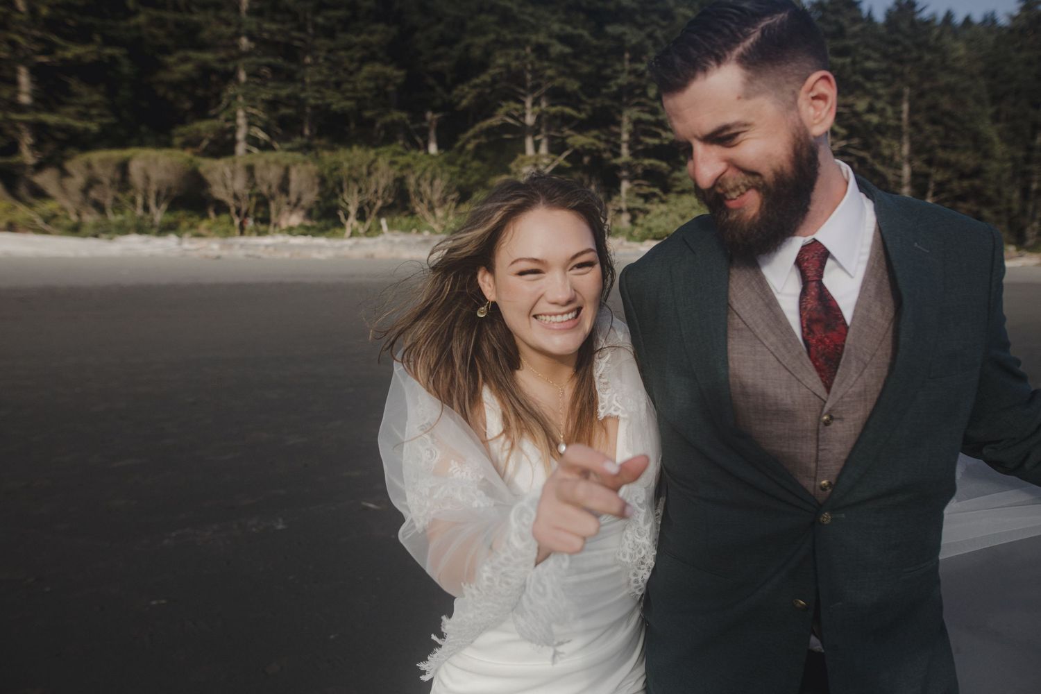 Joyful couple shares a candid laughing moment together at their outdoor beach wedding.