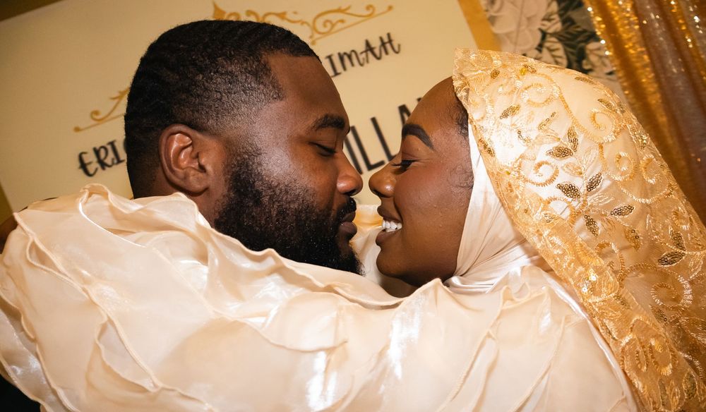 A couple shares a romantic moment at their wedding, dressed in elegant gold and white traditional attire.