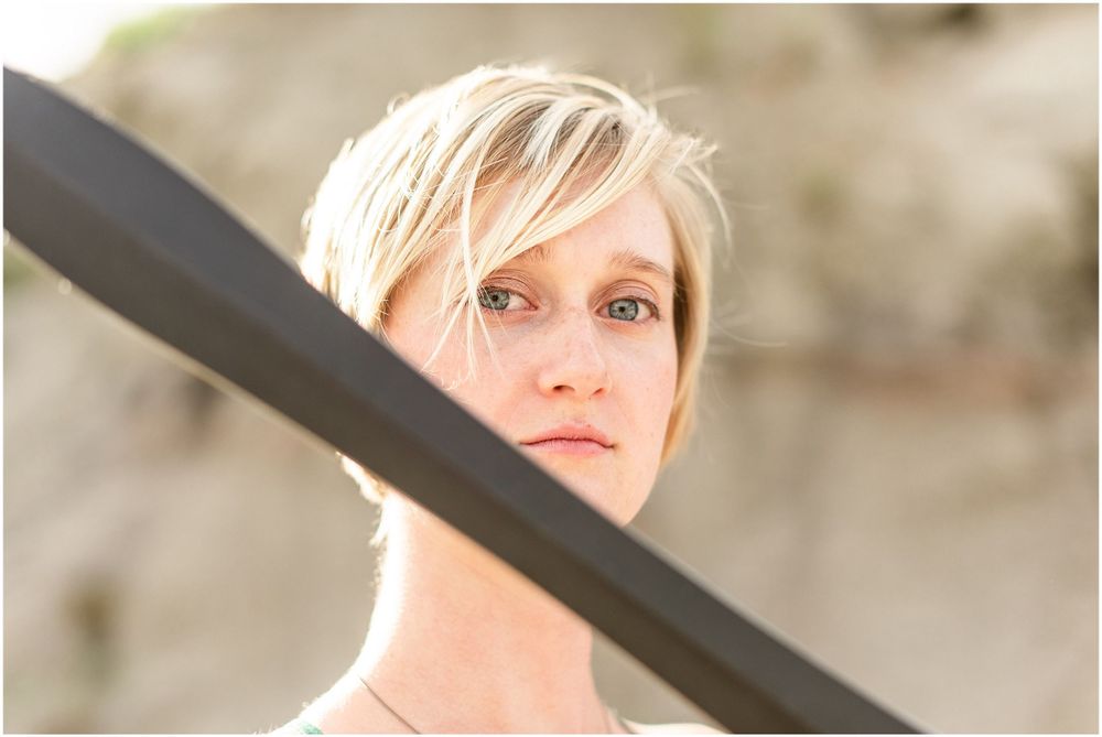 Artistic portrait shot through dark foreground element in natural lighting.