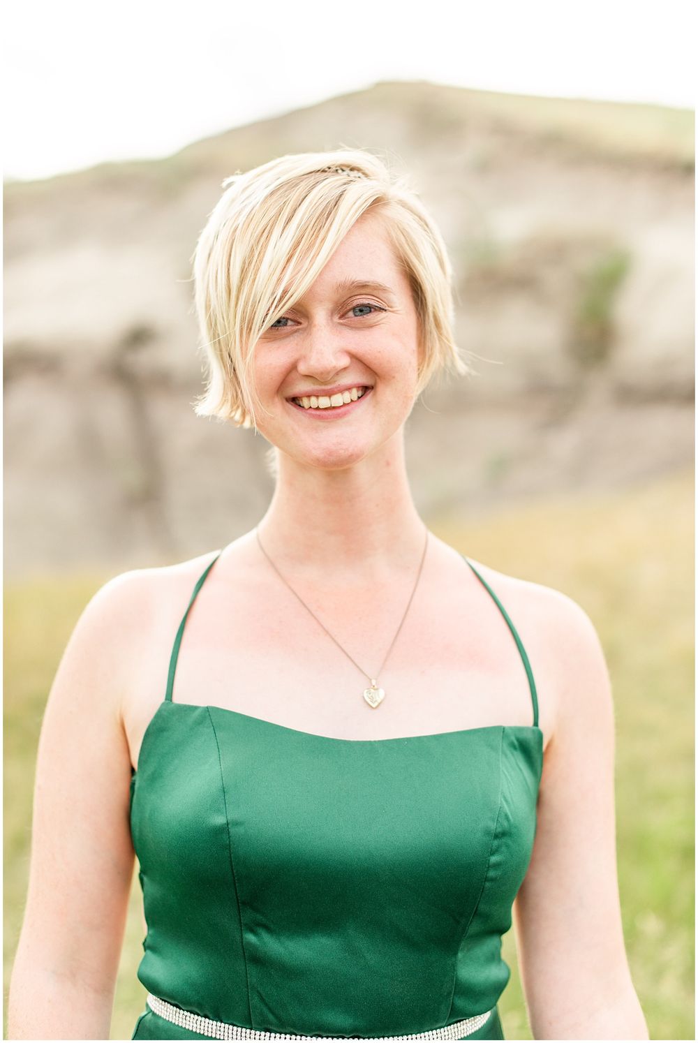 Portrait in emerald green dress against natural rocky landscape.
