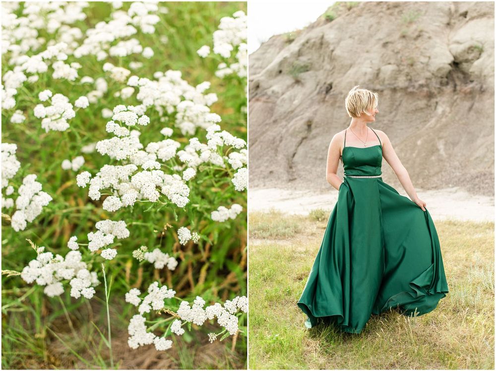 White wildflowers bloom beside figure in emerald gown twirling against rocky terrain.