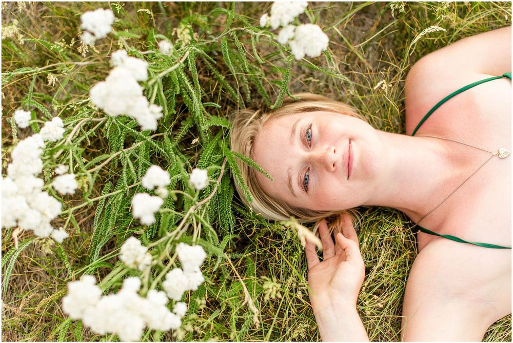 A person lying in grass surrounded by delicate white flowers.