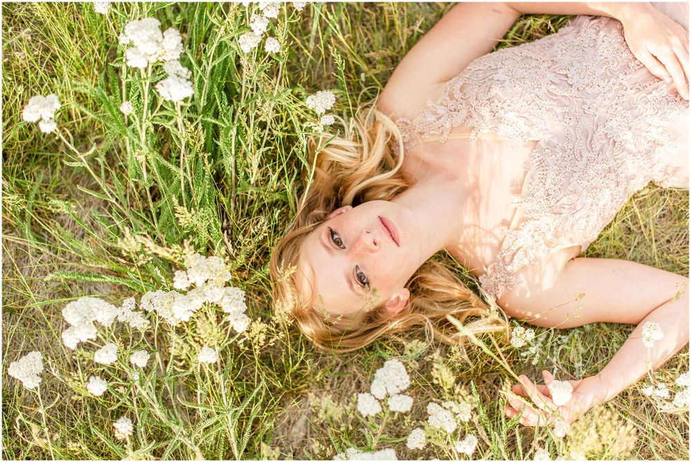 A person lies in flowering meadow grass wearing a delicate lace dress.