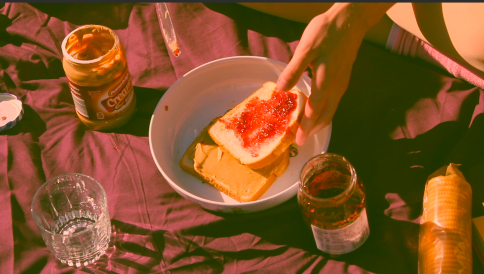 Toast with jam or preserves being prepared alongside drinks on a table.