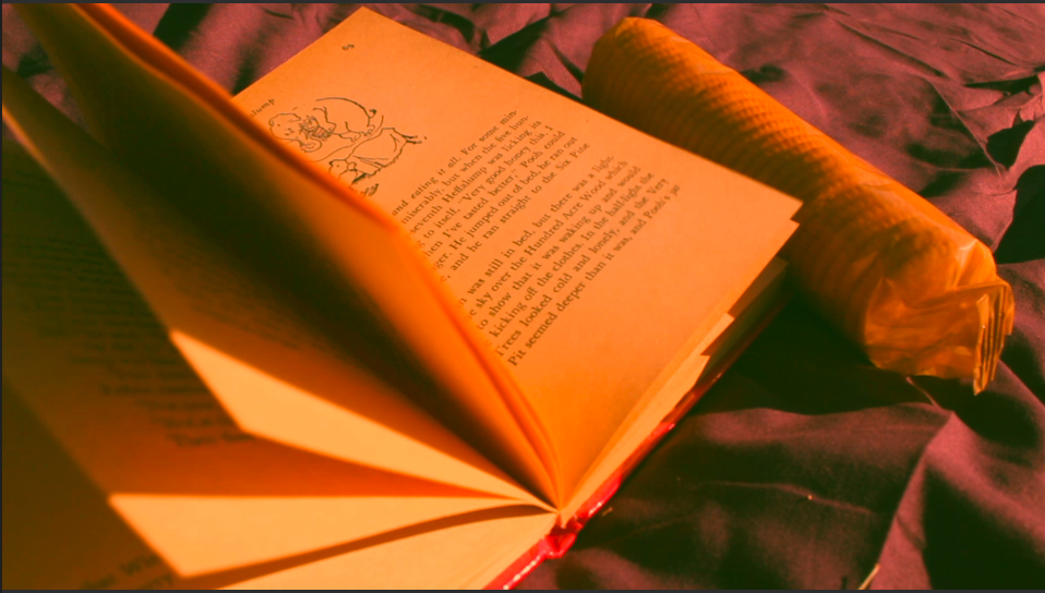 Close-up of an open book with pages illuminated by warm orange light.