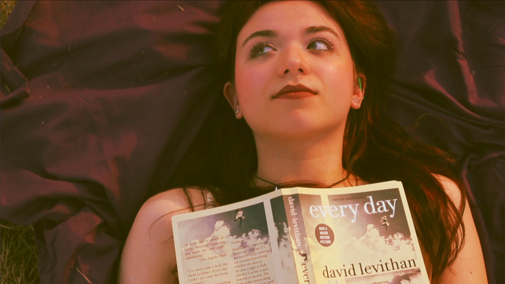 Someone lying down while reading a book with dramatic lighting.