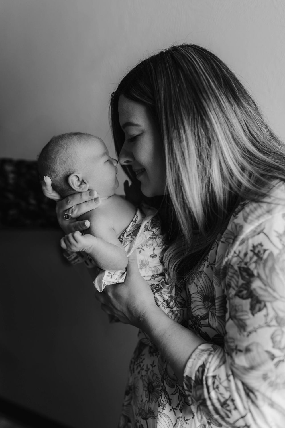 Black and white intimate portrait of mother and newborn sharing a tender moment.