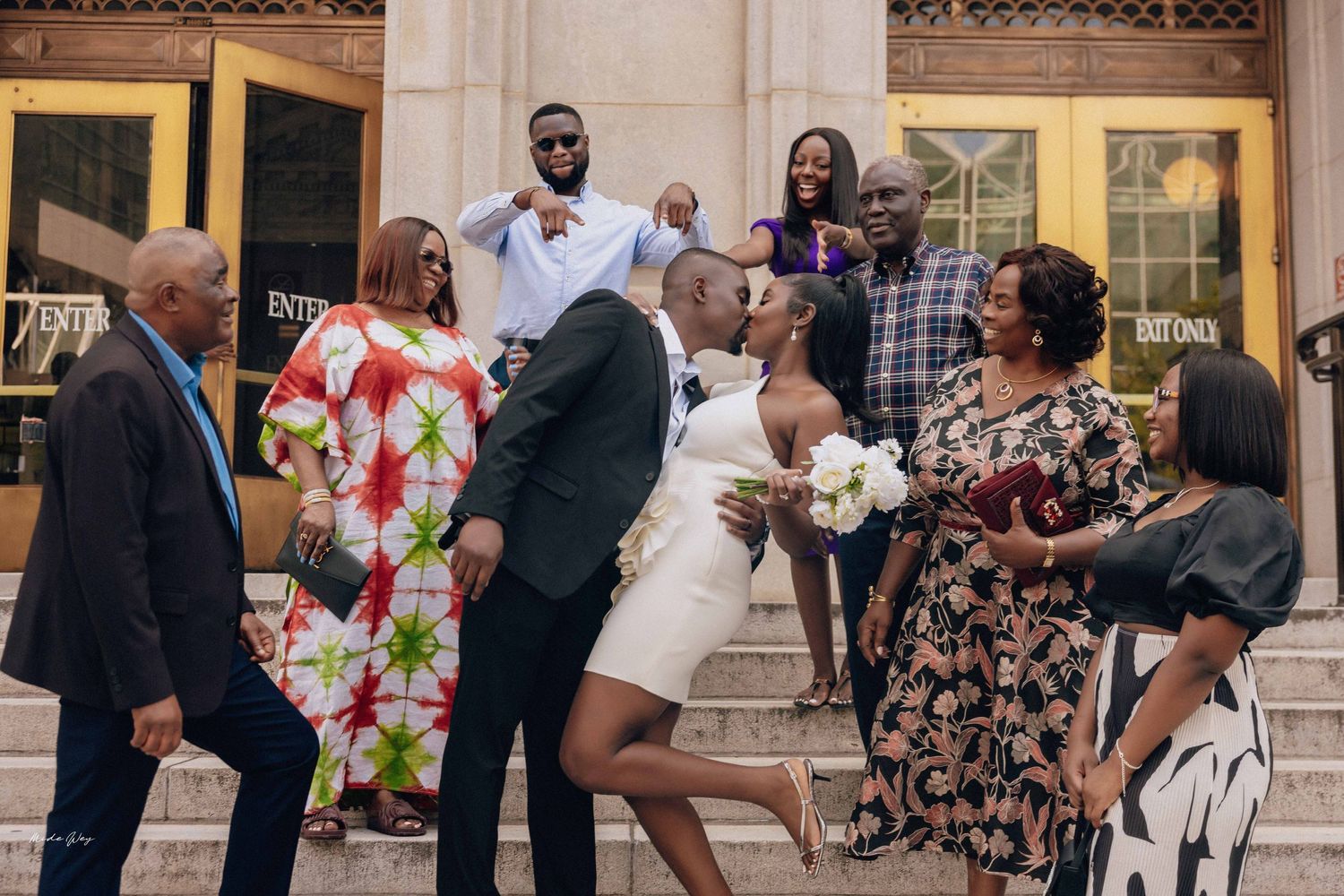 Group of family members dancing and celebrating on outdoor steps of a building.