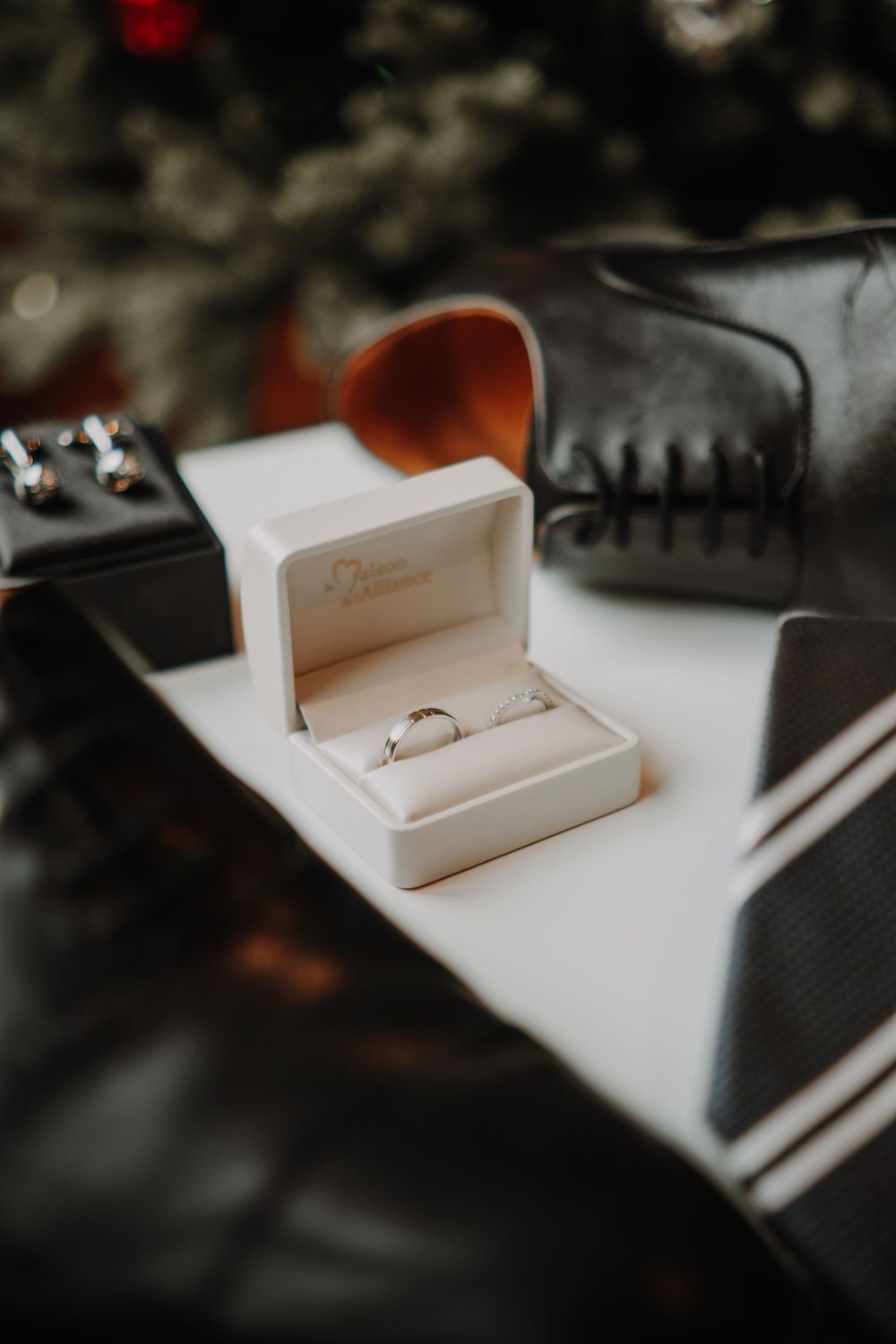 A series of photos showing a white ring box at different angles on a white surface with blurred dark background.
