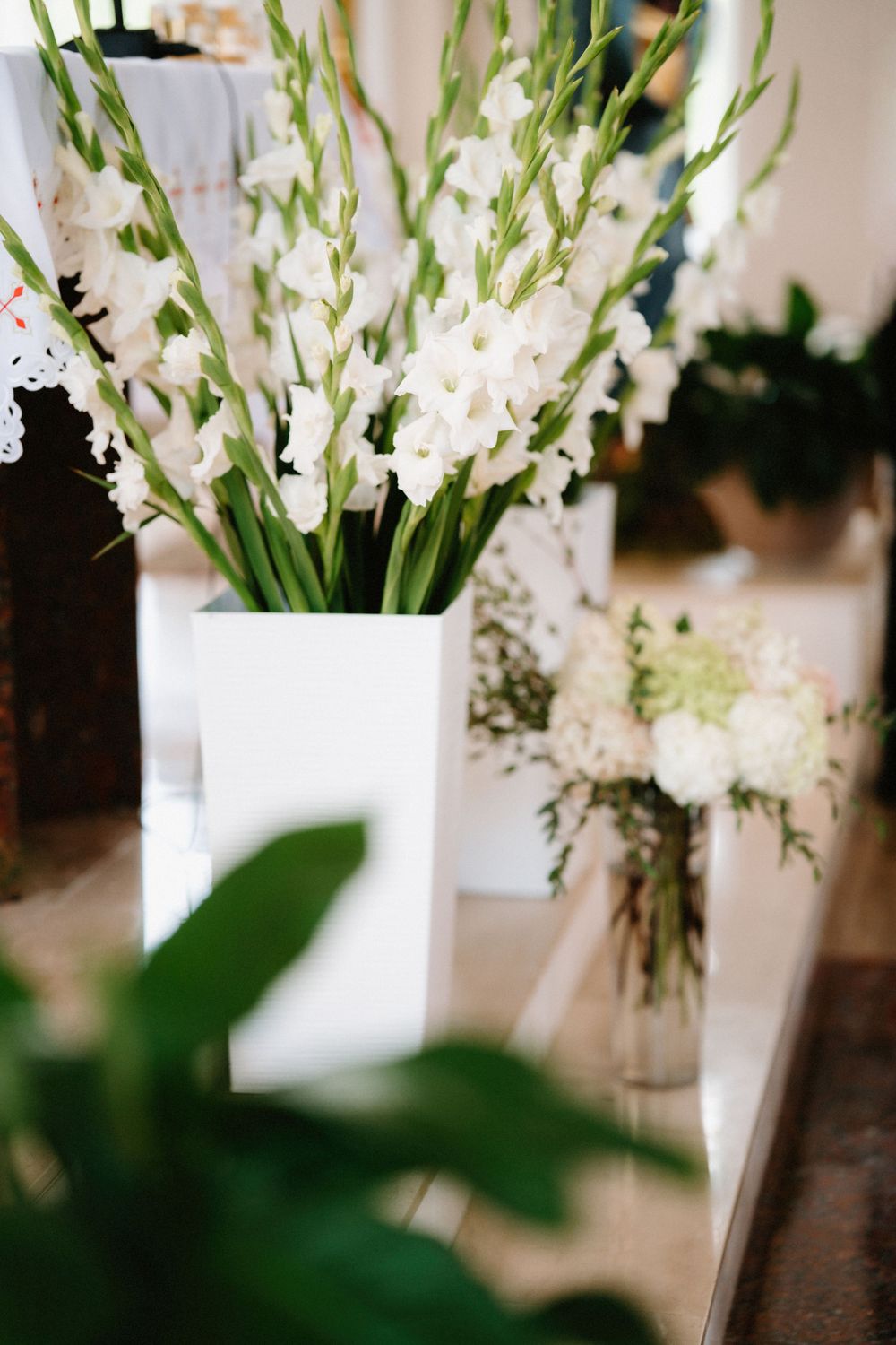Elegant white floral arrangements with delicate blooms in glass vases on dark wooden surface.