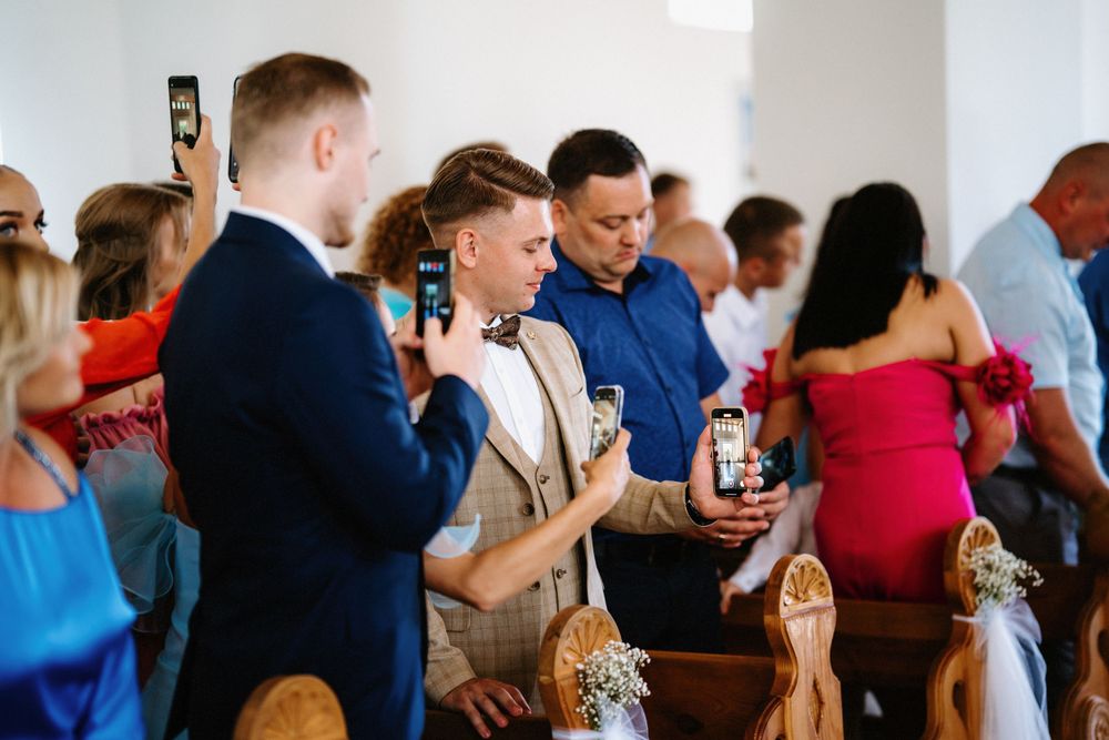 Wedding guests gathered in church pews during ceremony.