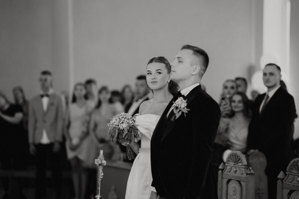 Black and white photo of wedding ceremony with guests in formal attire.