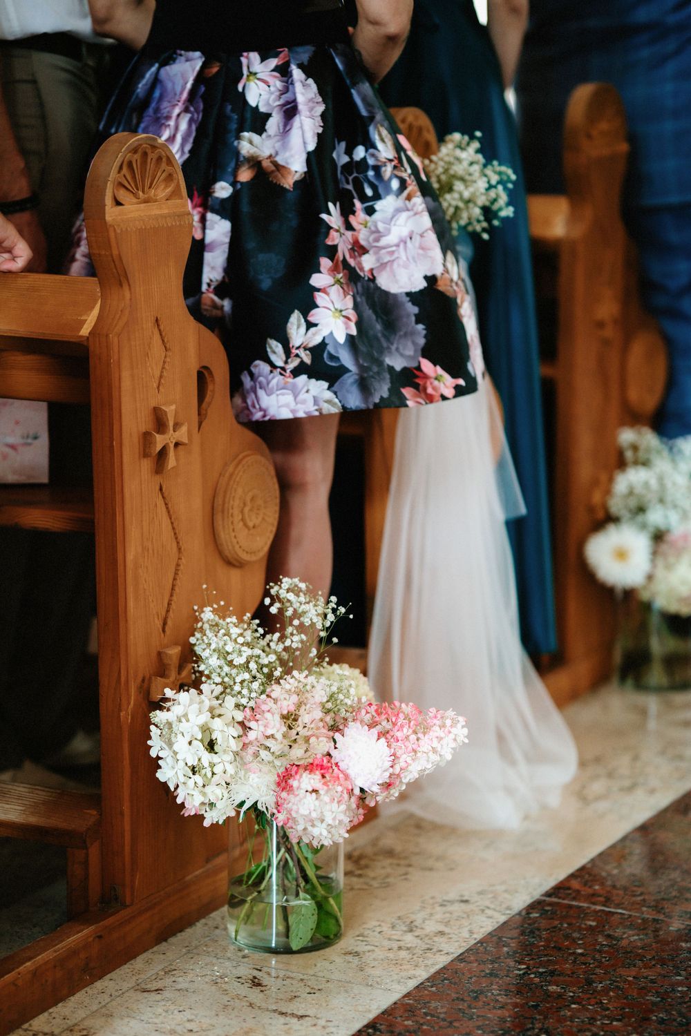 Church pew decorations with mason jars filled with baby's breath and pink flowers.