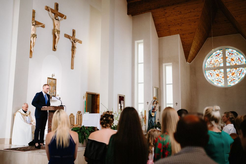 Church interior with wooden beams and stained glass windows during wedding ceremony.