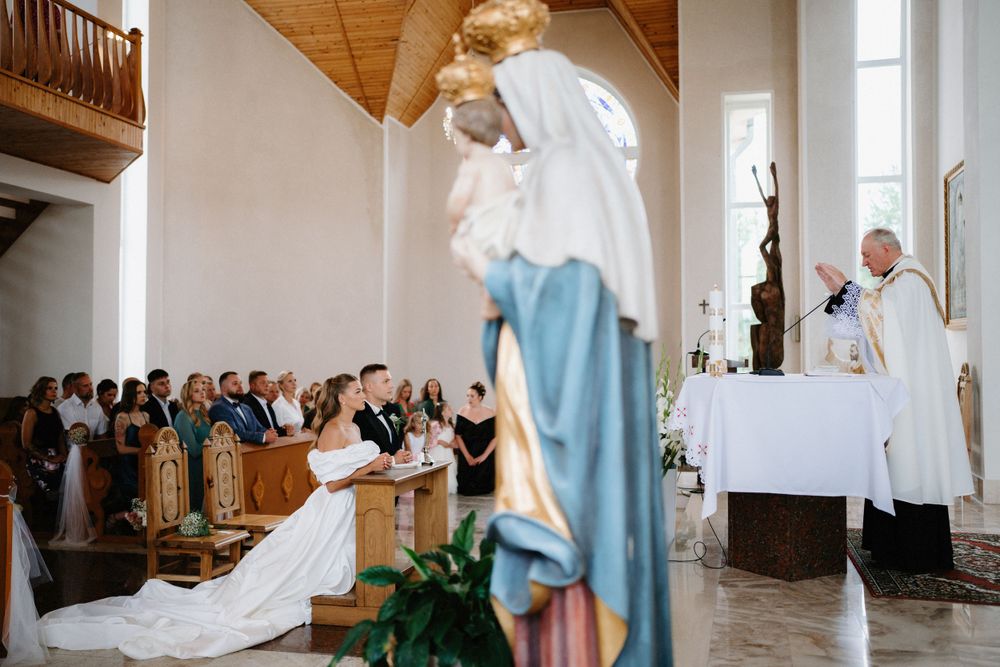 Traditional Catholic church wedding ceremony with wooden beams and white walls.
