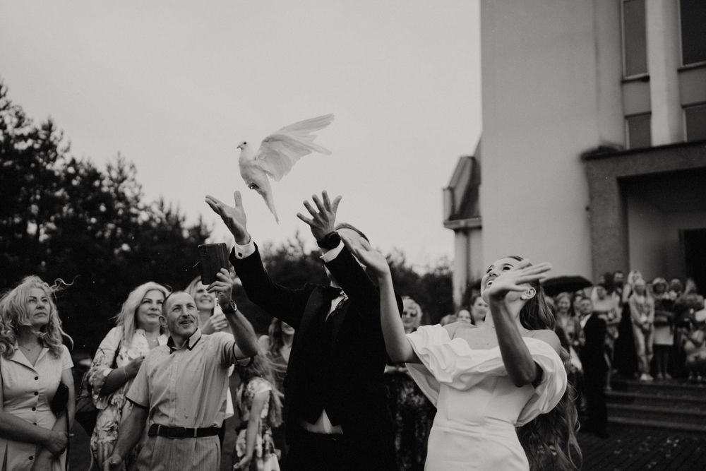 Wedding guests celebrating outdoors by throwing white items in the air.