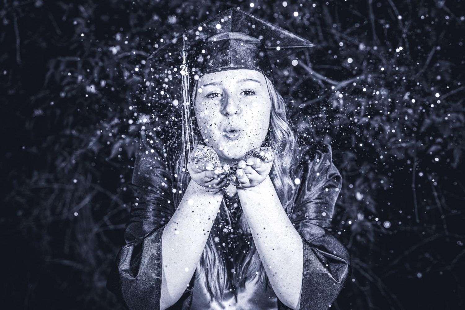 Person blowing glitter in magical black and white portrait with sparkles.