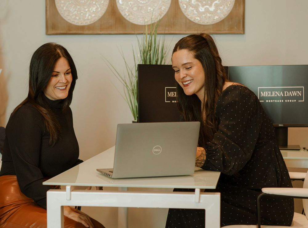 Team members collaborating at white desk with laptops and office decor.
