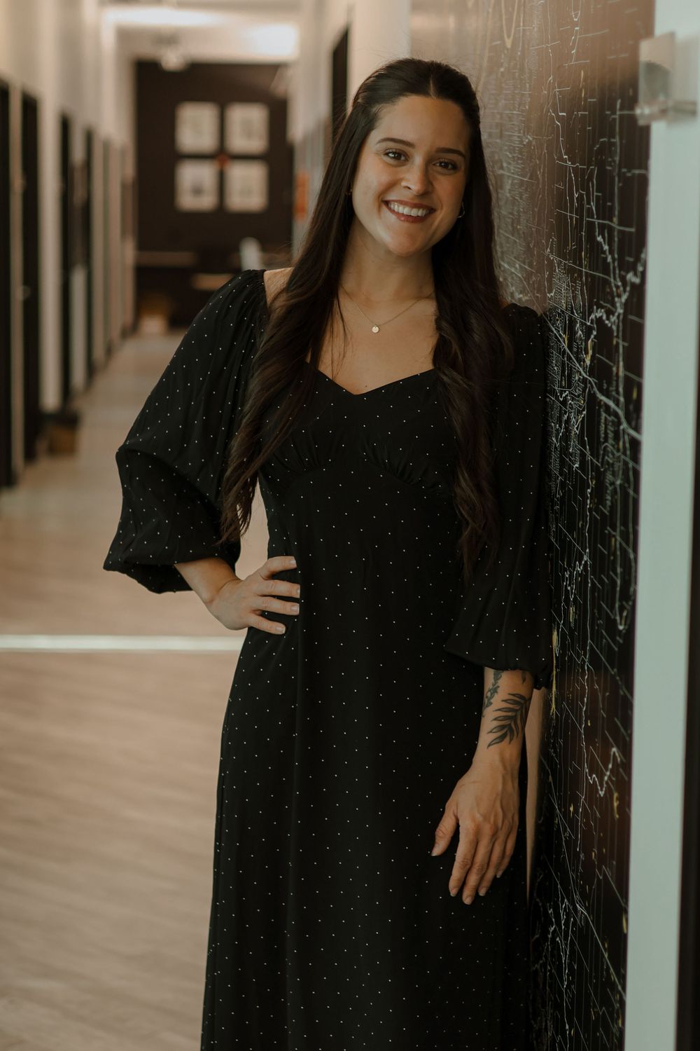 Professional portrait series showing woman in black dress posing against textured wall in hallway.