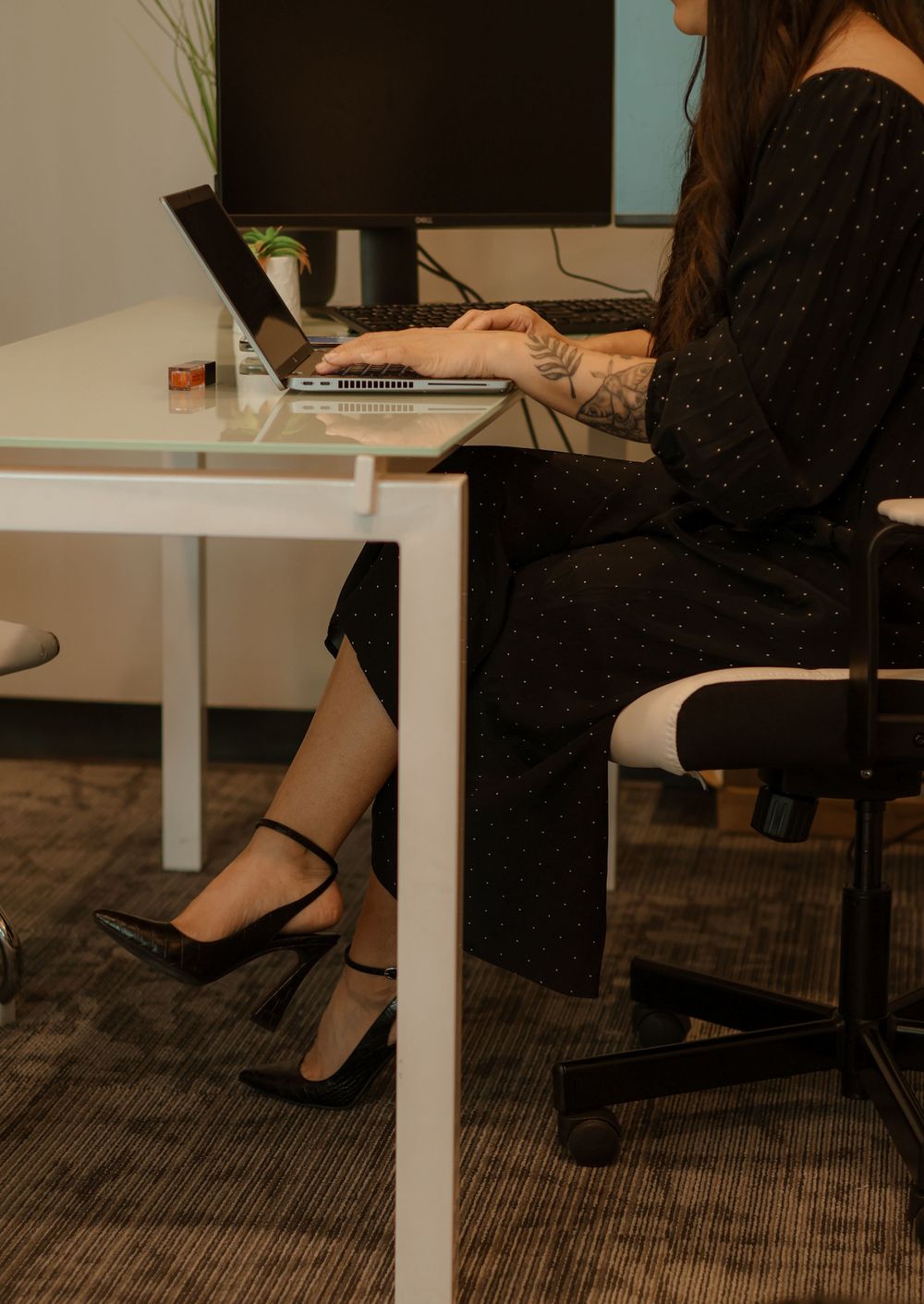 Person working at white desk with laptop showing professional office environment.