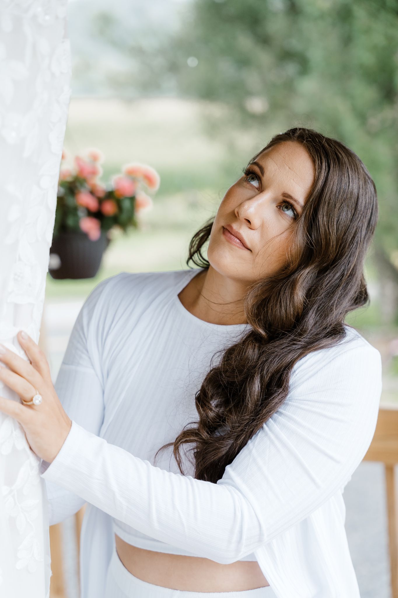 Portrait of someone in white against a soft garden background with pink flowers.