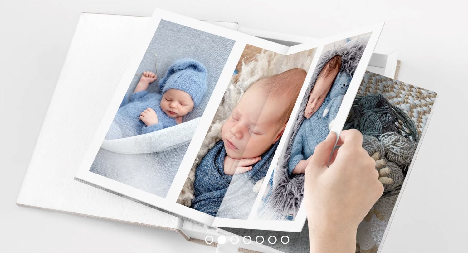 Hands flipping through a photo album displaying high-quality, professional portraits of a baby. vivitu personalised photobook