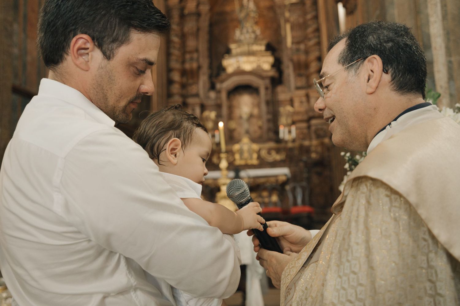 A series of priests in white robes perform a religious ceremony at an ornate church altar.
