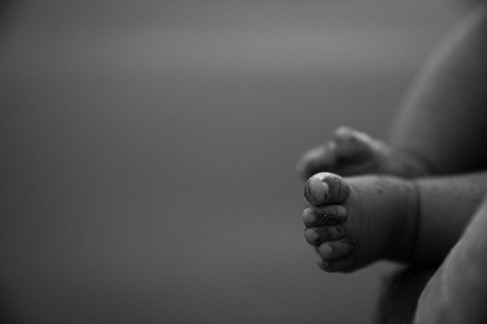 Black and white close up of tiny baby feet against a soft blurred background.