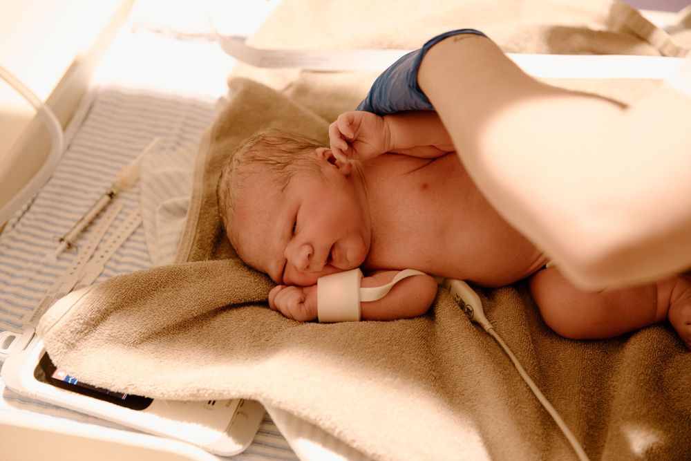 Newborn sleeping peacefully on a warm blanket in soft lighting.