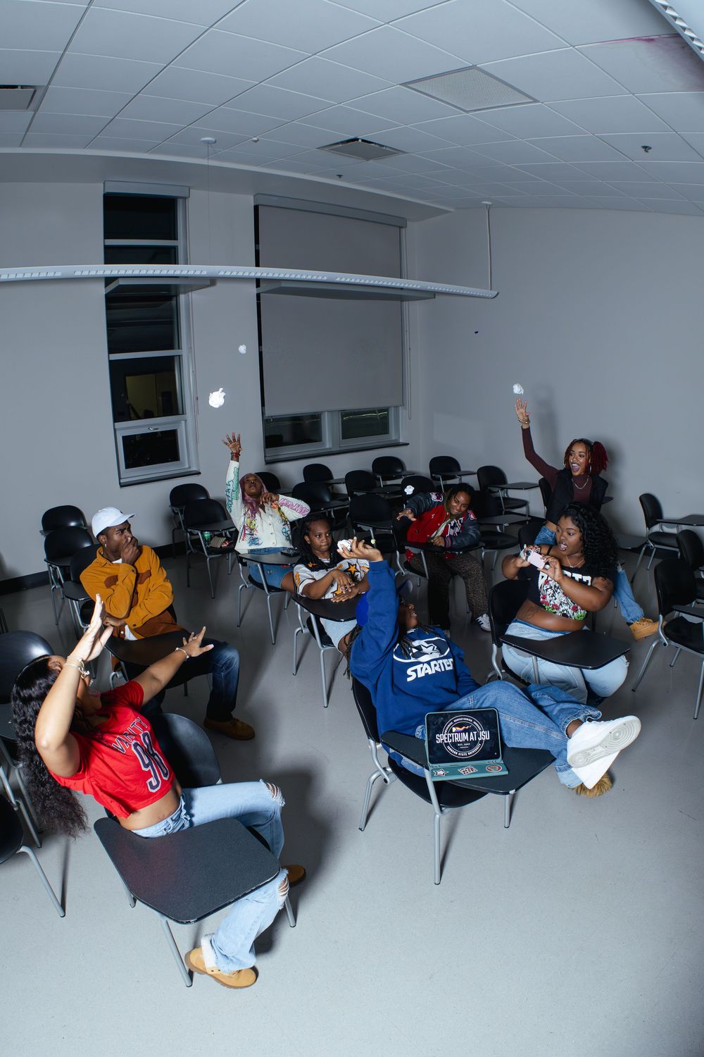 Dynamic group photo with people making playful poses in studio chairs.