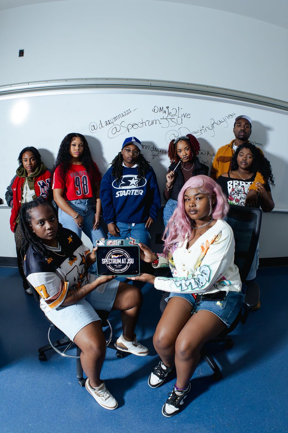 Friends lounging together on chairs in studio setting wearing casual streetwear.