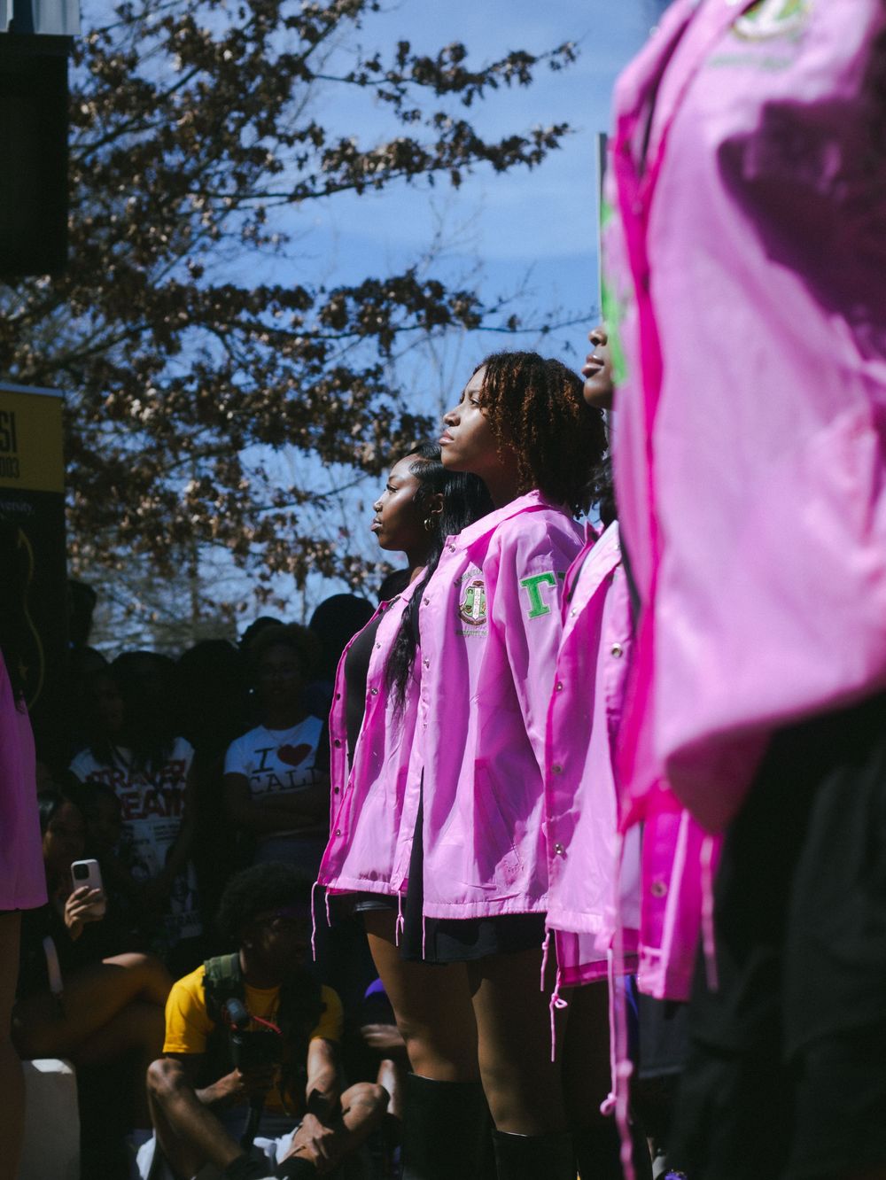 Group wearing bright pink shirts standing in formation outdoors.