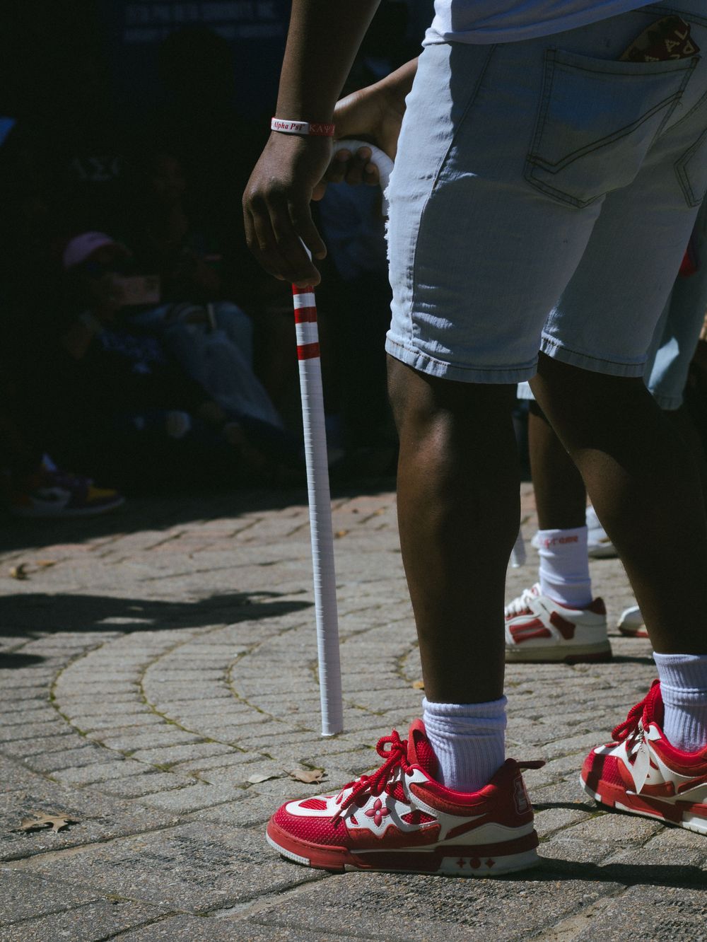 Close-up of red sneakers and a cane during an outdoor performance.