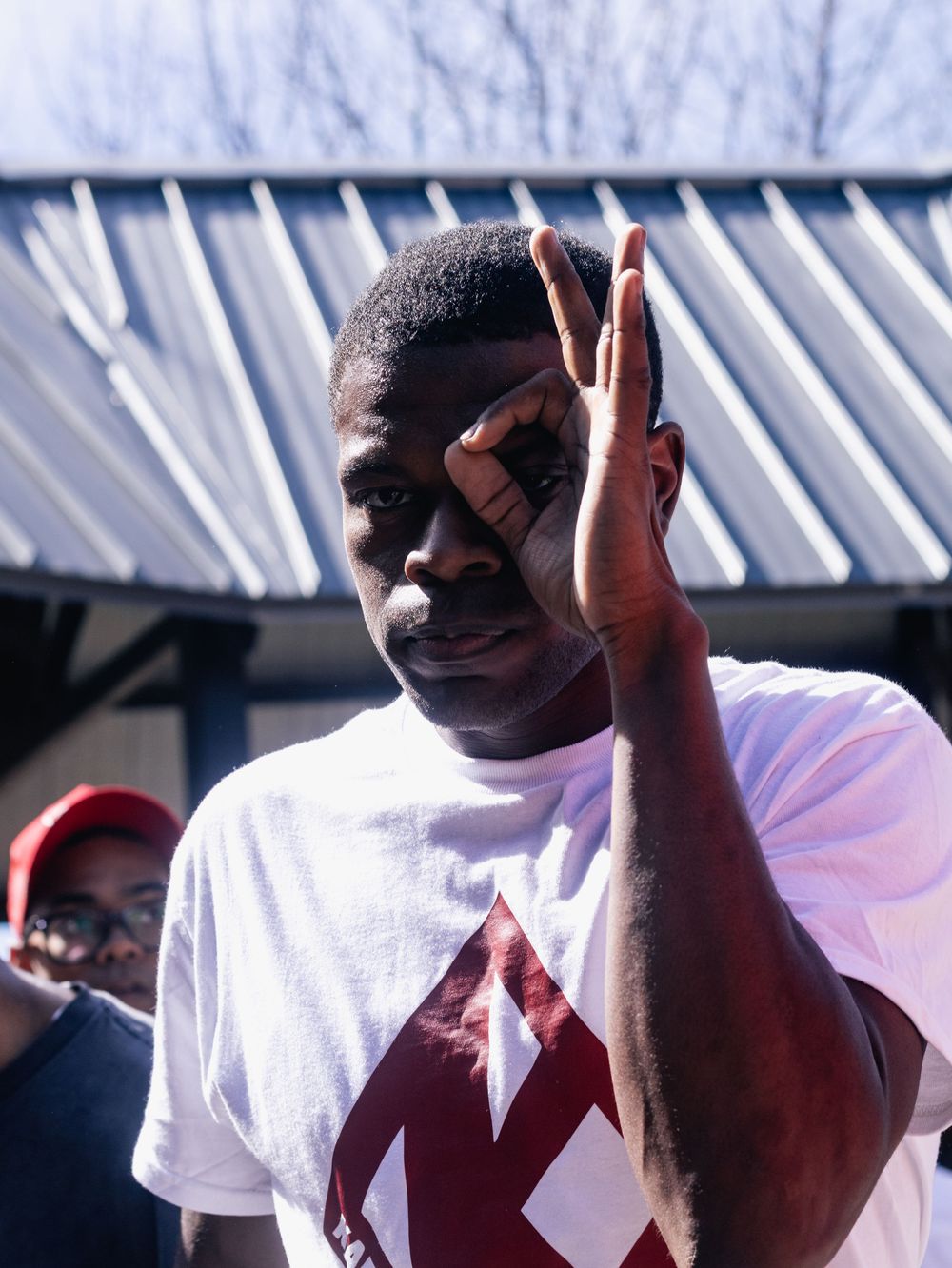 Person in white shirt gesturing during an outdoor gathering.