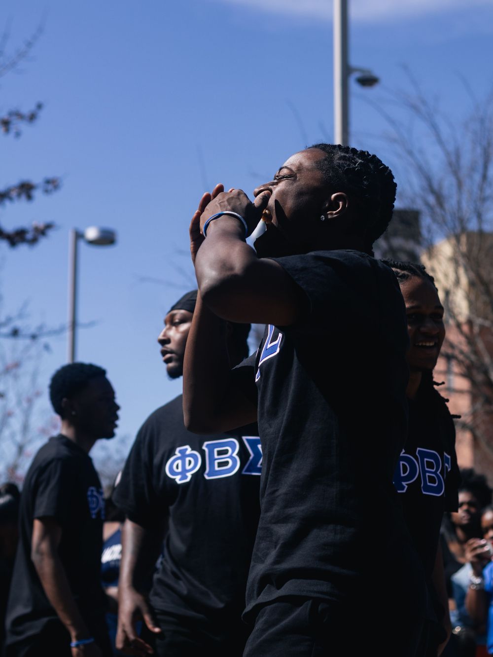 Students in black Phi Beta Sigma shirts gather at an outdoor event.