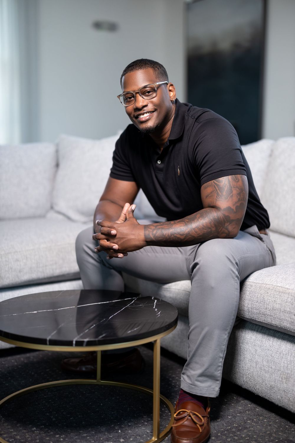 Casual business professional seated on grey couch with coffee table.