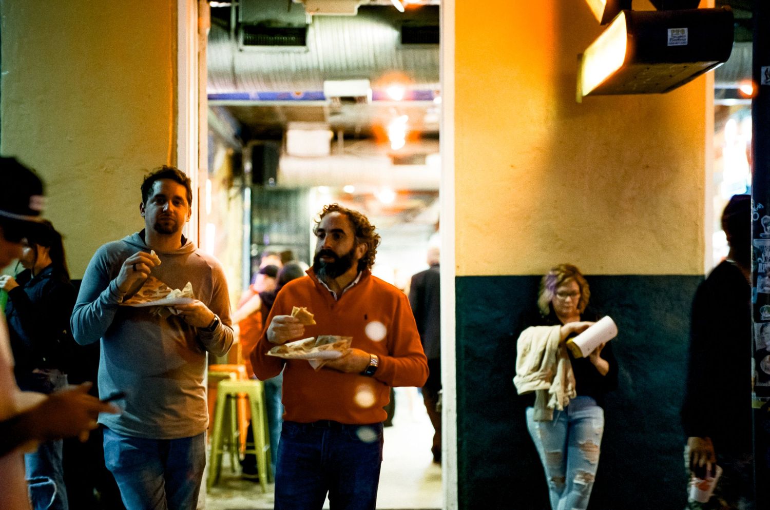 Group of people gathered in a warmly lit indoor hallway or corridor.