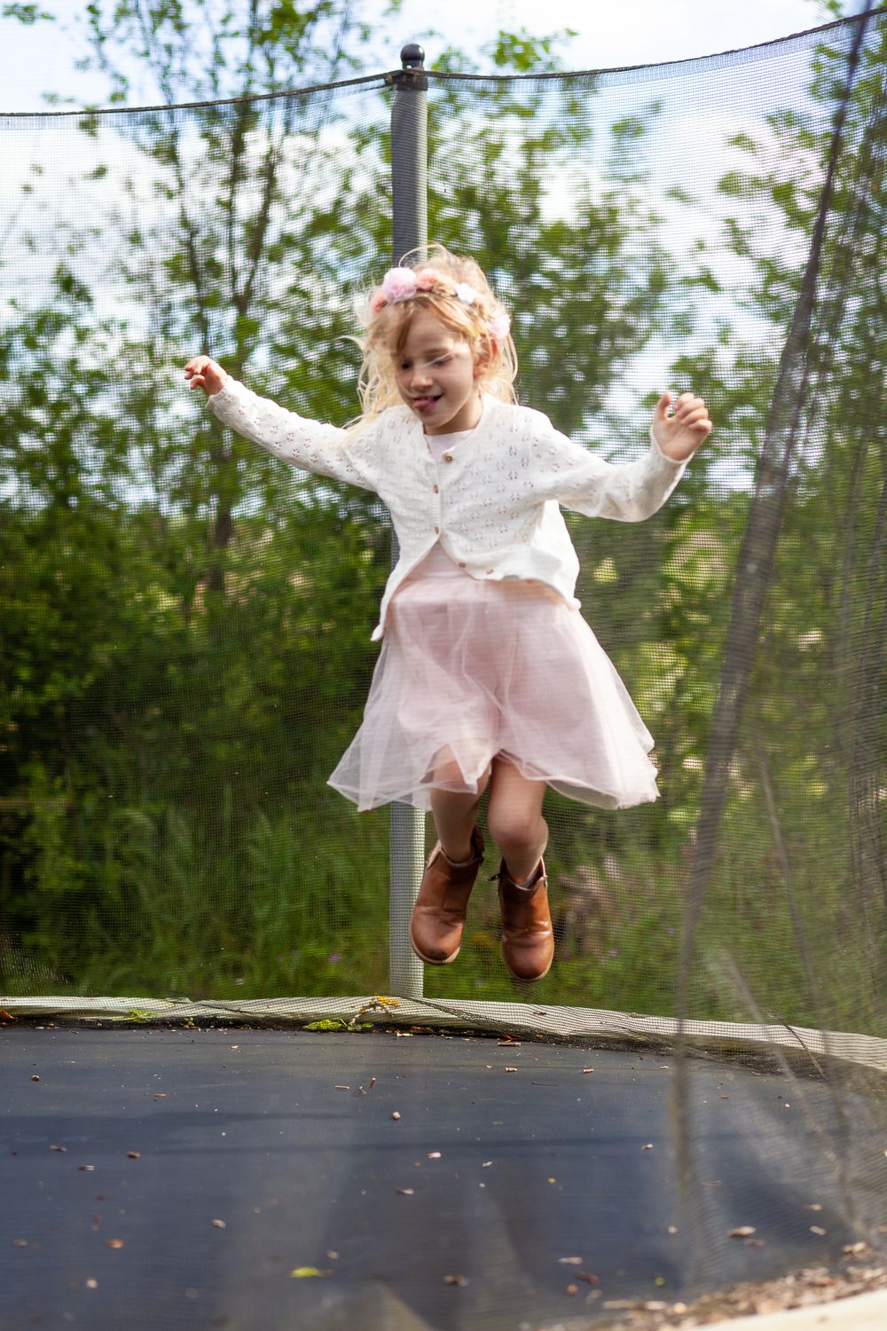 A sequence of joyful bouncing on a trampoline in a backyard with trees in the background.