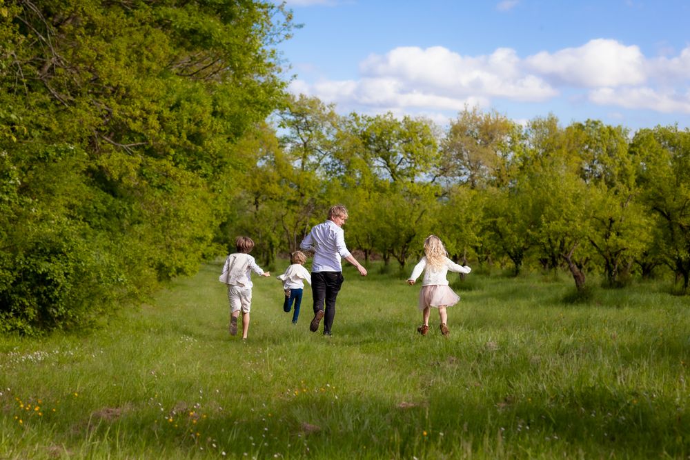 Family walking together through a green orchard on a sunny spring day.