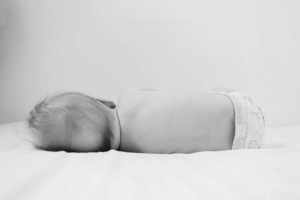 Minimalist black and white photography of resting figures against white background.