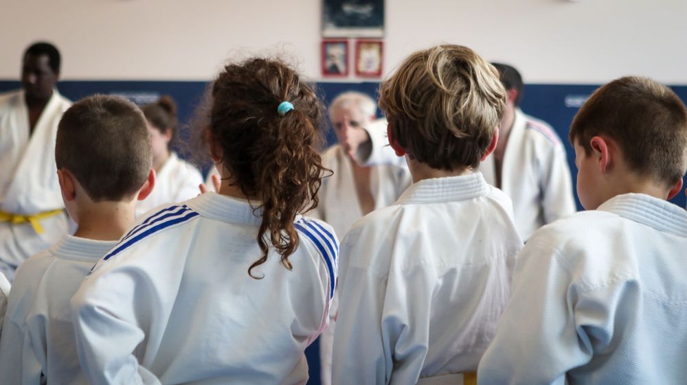 Students in white martial arts uniforms standing in line at training class.