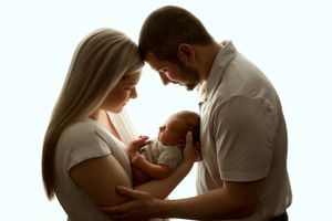 Intimate family moment silhouette with tender embrace against light background.