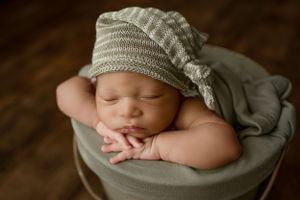 Sleeping newborn wearing knit hat during professional portrait session.