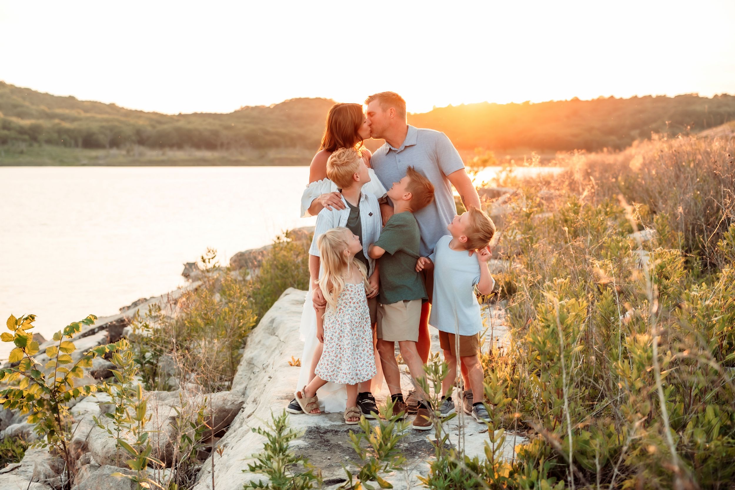 Family enjoys sunset moment together in golden wildflower field during outdoor photo session.