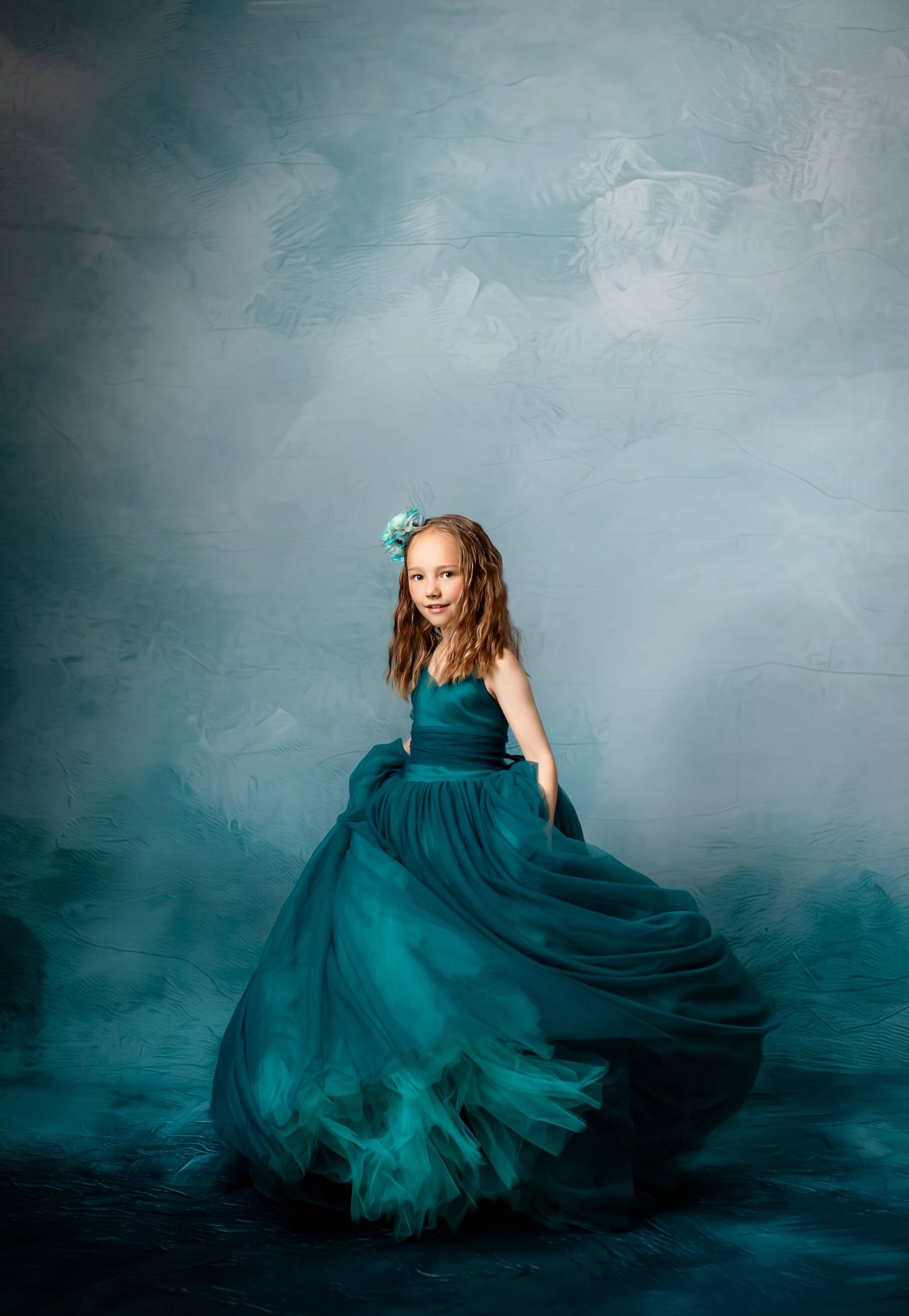 Dramatic portrait in flowing navy ball gown against dark atmospheric background.