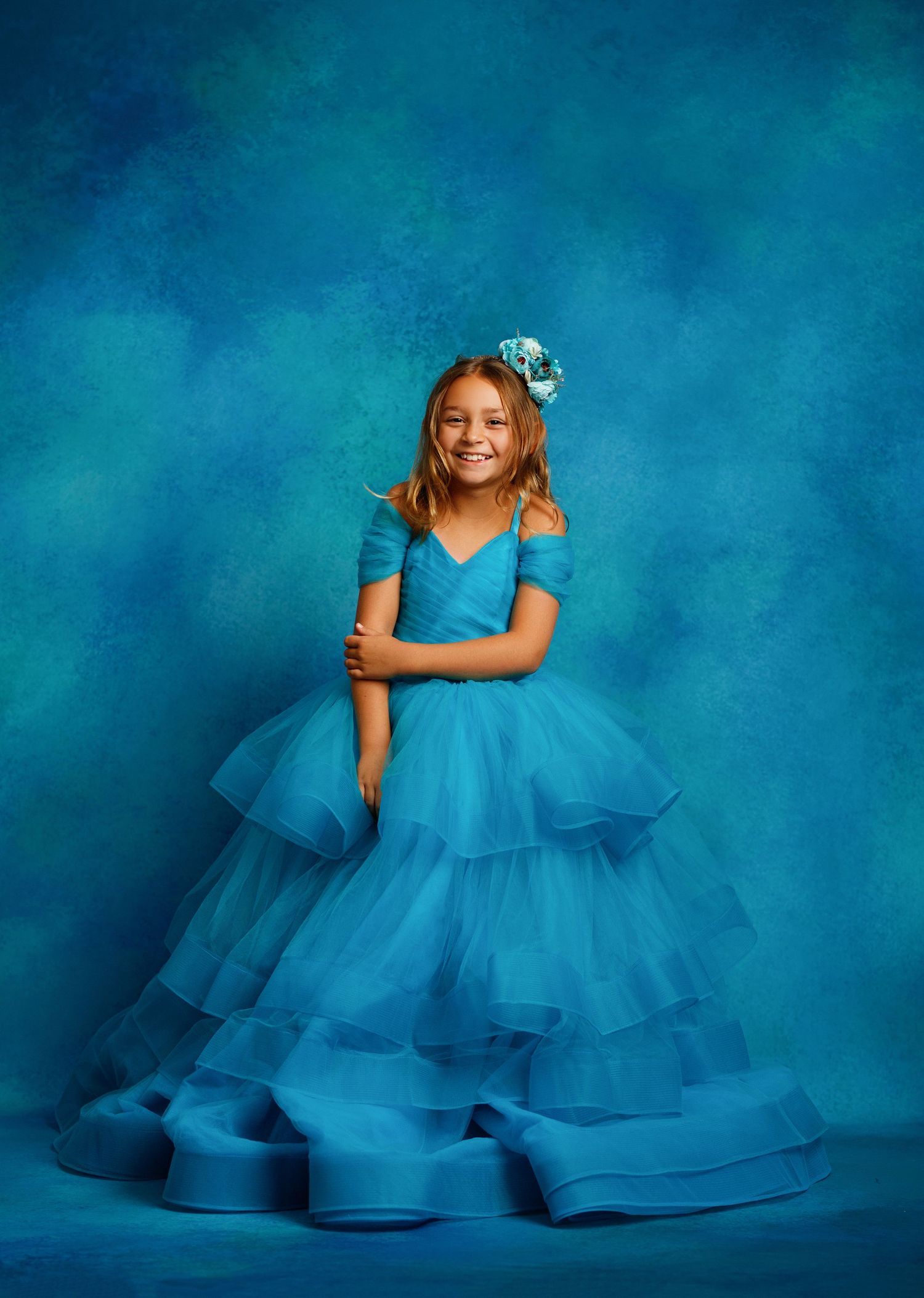 Dramatic portrait in flowing navy ball gown against dark atmospheric background.