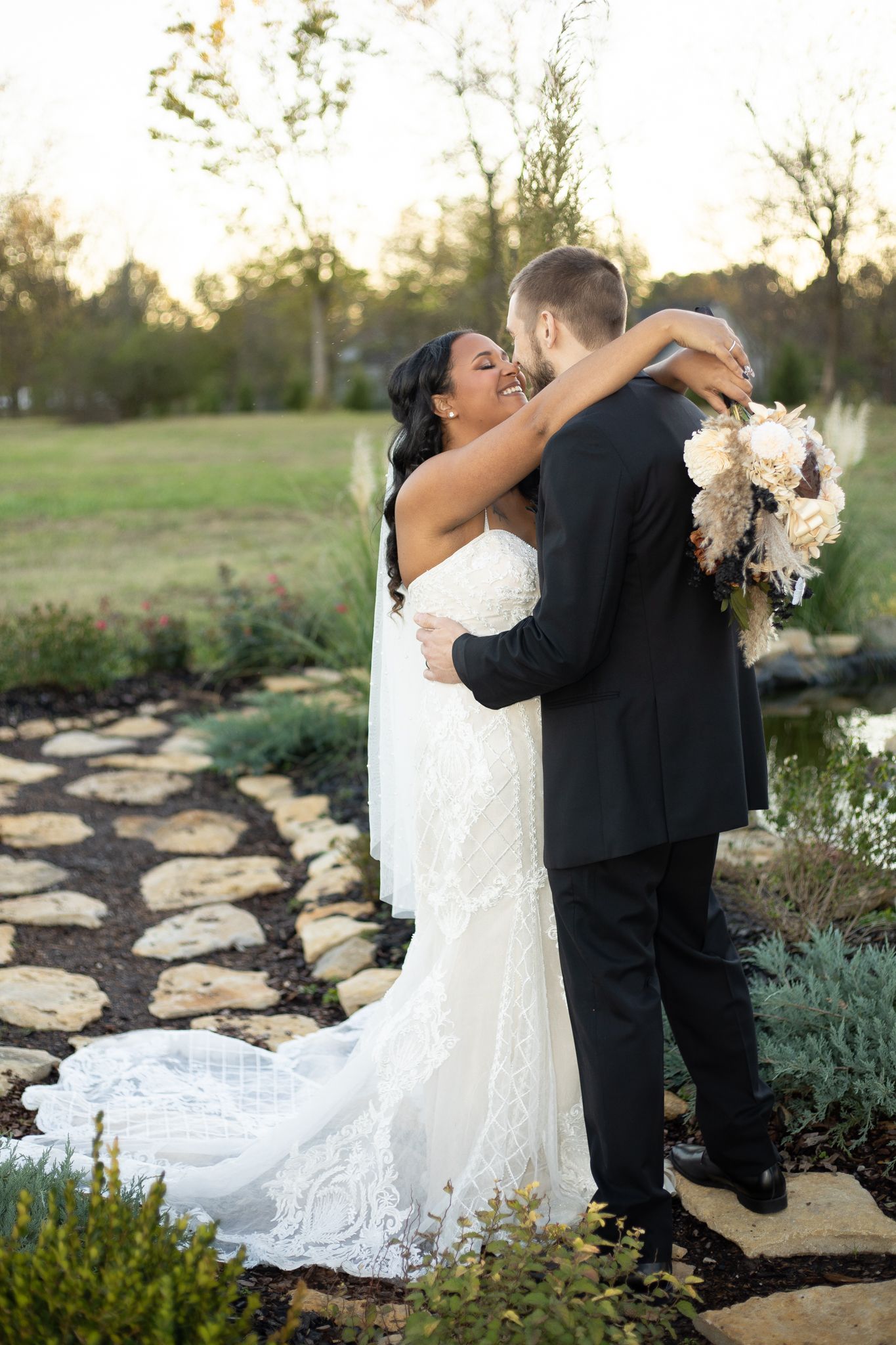 A romantic wedding moment captured on a stone pathway with a bouquet of white flowers.