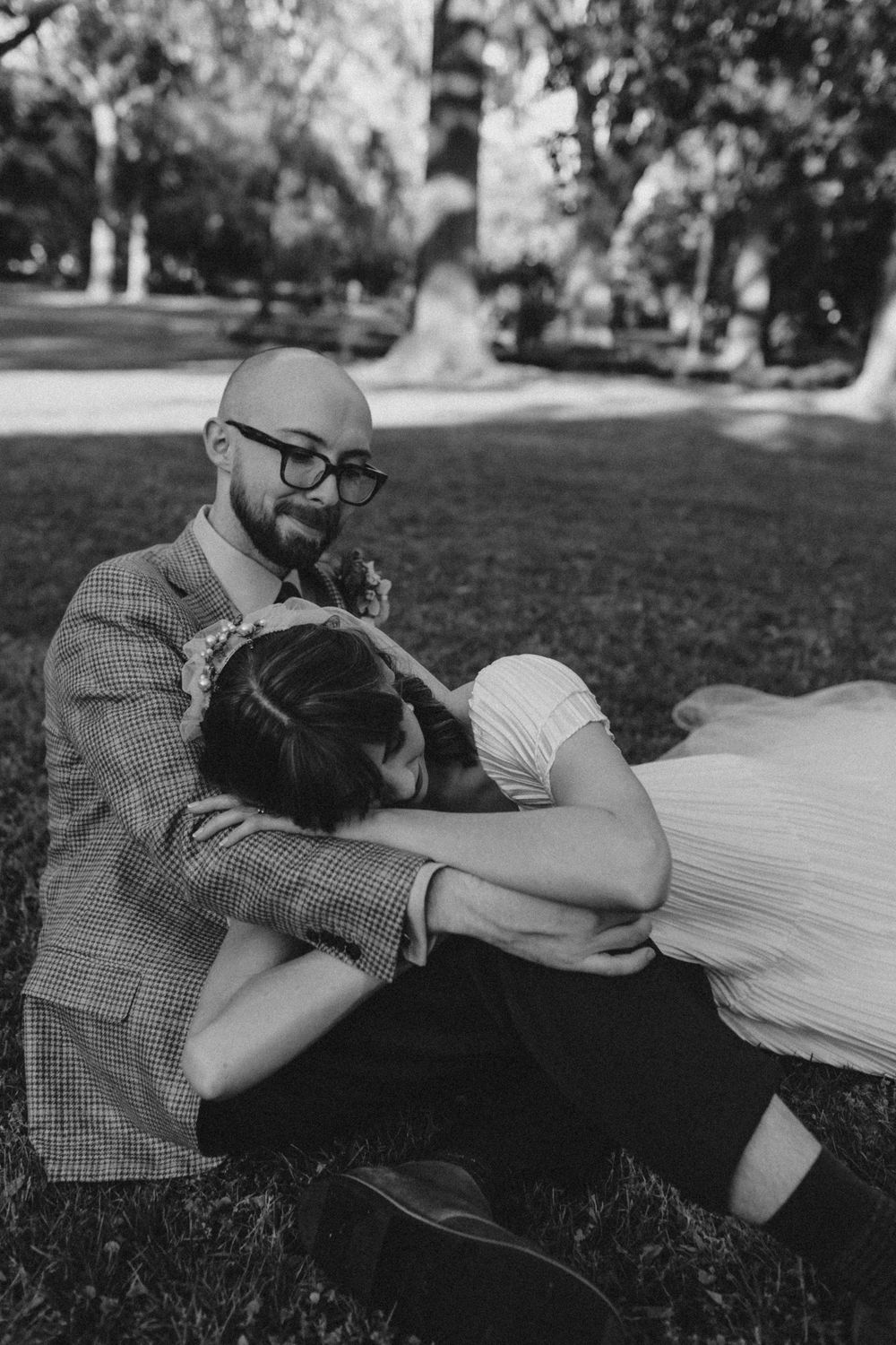 A bride lies on the knee of her groom at Forsyth Park after their ceremony