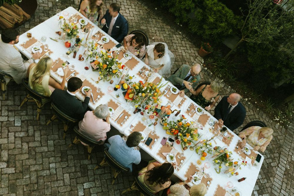 An overhead view of a wedding dinner table full of guests and food