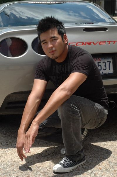 Casual portrait with Corvette sports car in background on sunny day.
